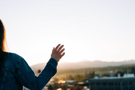 Woman with Hand Extended in Prayer Over the City