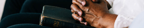 Hands Folded in Prayer on a Bible