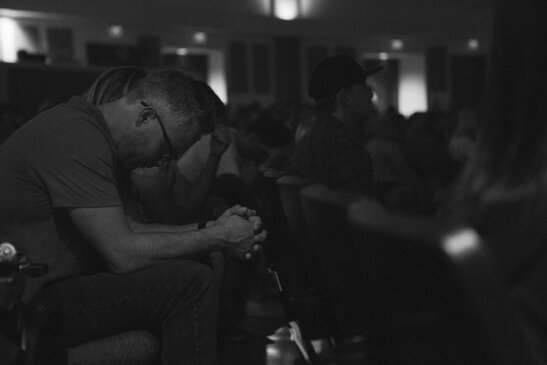 Man Bowing Head in Prayer During Church Service