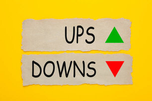 Ups And Downs written on old torn paper on yellow background. Two arrows 'up' and 'down'.