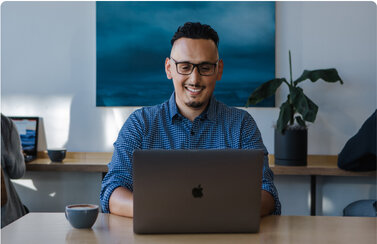 Smiling man using his laptop with coffee