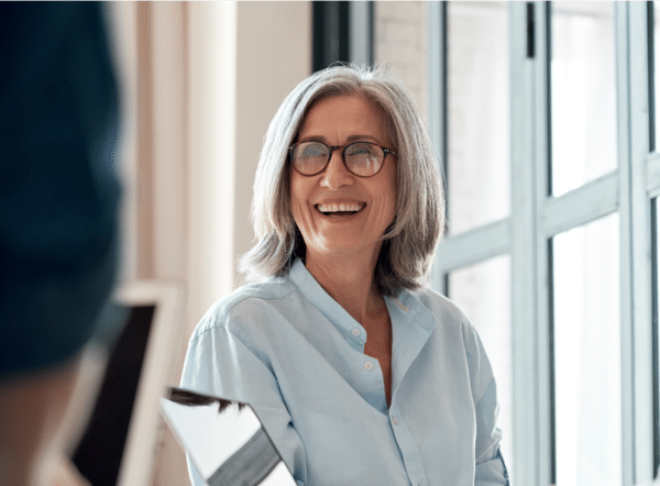 Middle aged woman with gray hair smiling with an open mouth.