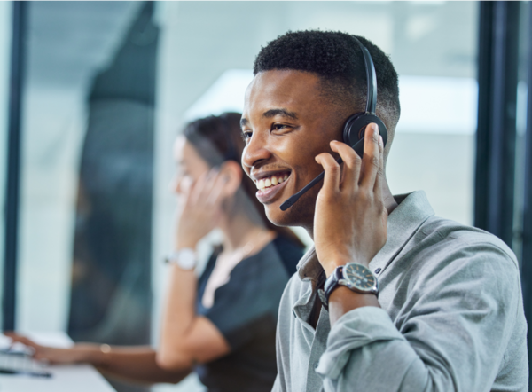 Call center with one person in focus with a headset on talking on the phone.