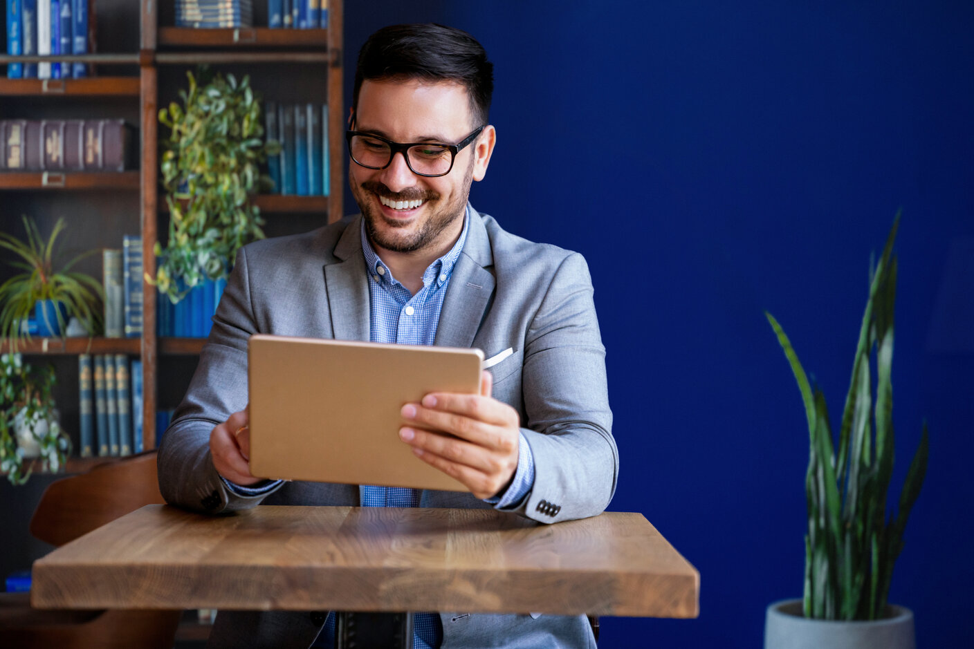 Young smiling successful business man, entrepreneur in formal business suite working on tablet