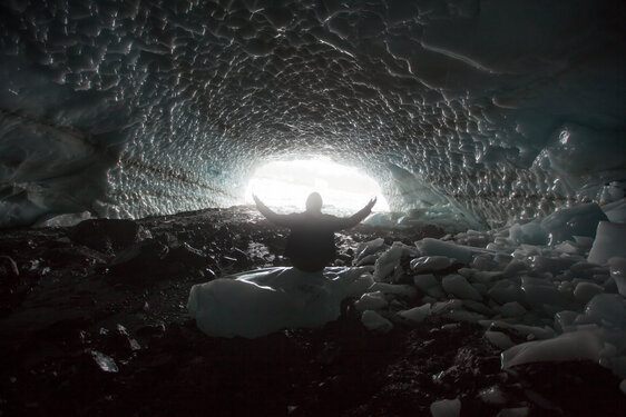 Man raising his hands in worship in an ice cave
