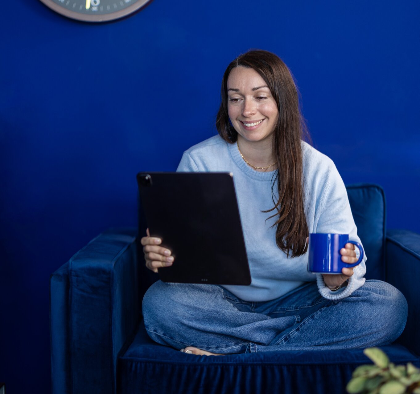 A woman smiling while using a tablet in a library setting.