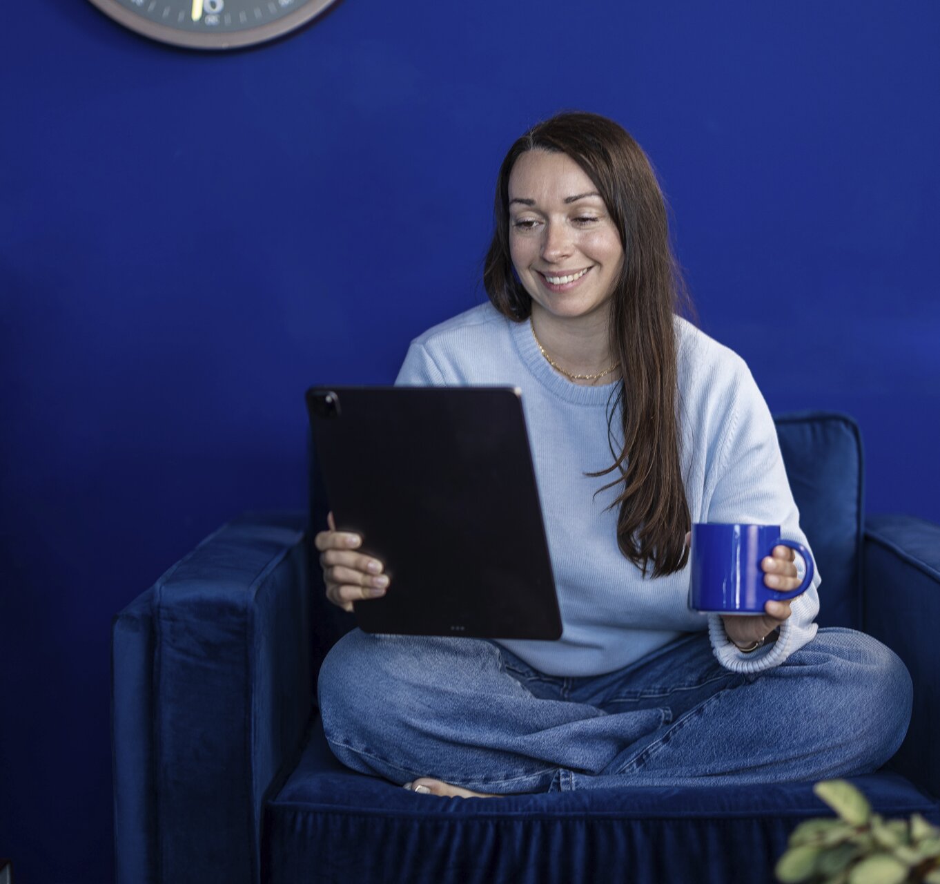 A woman smiling while using a tablet in a library setting.
