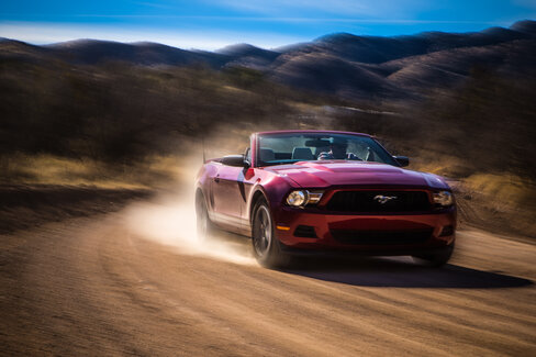 Red Mustang on a dirt road
