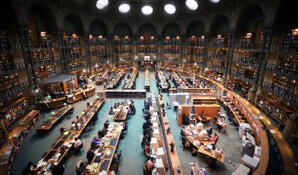 An image of a large library with many people studying, seen from the view of a high-up balcony