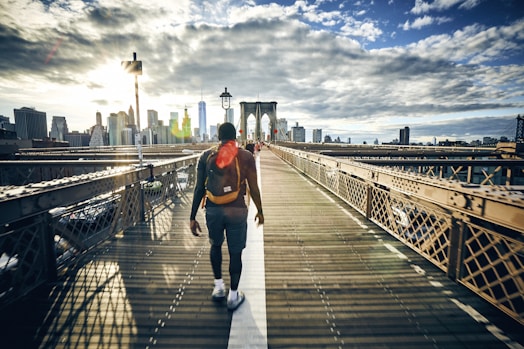 Man walking back from Brooklyn to Manhattan with New York skyline in the background.
