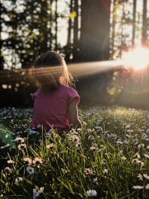 My family was enjoying some time on a hike in a wooded area.  The way the light was coming through the trees and across the grass and daisies was making me itch to capture the moment. 

I got down on my stomach in the grass to capture this photo of my daughter Ellie. All I had with me that day was my iPhone X which was still a champ for captuing the moment perfectly. I just love the way the end of the day sunlight was making her glow.  To me this photo perfectly captures summer, childhood, and my sweet girl, who shines brighter then the sun.