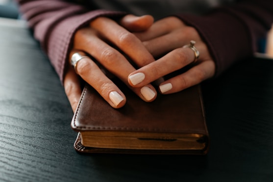 Woman's hands folded in prayer on a Bible