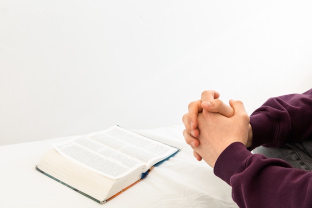 Person praying with open Bible.