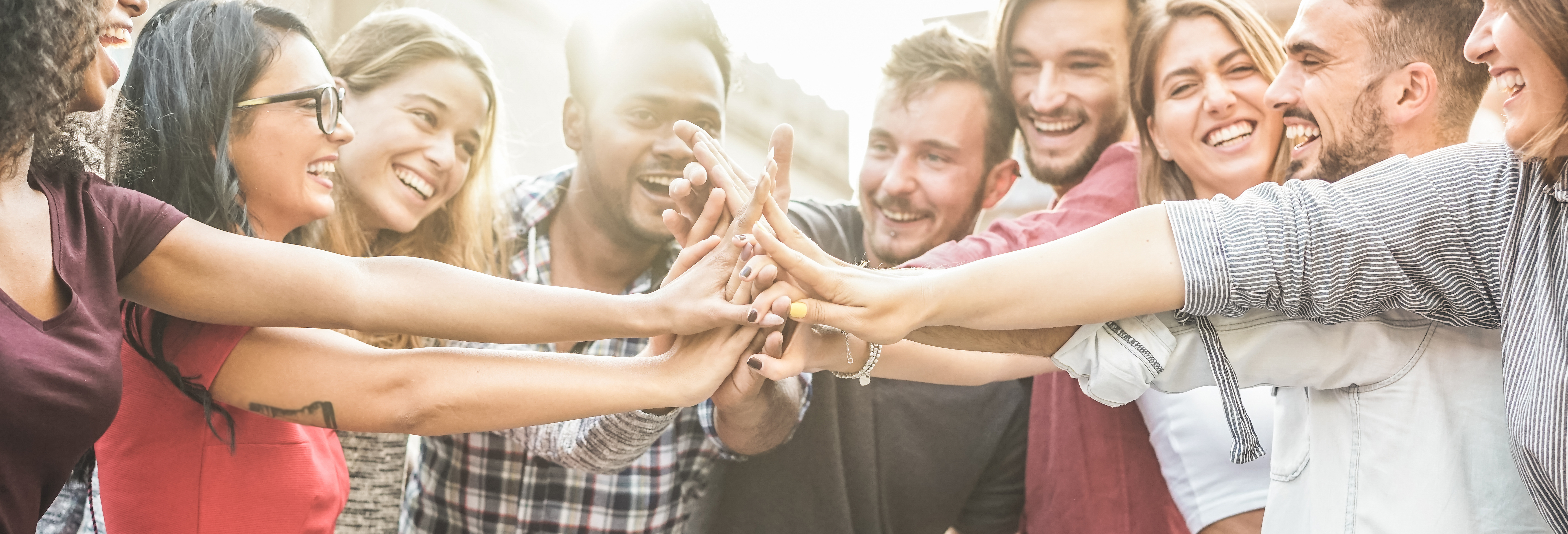 Young happy people stacking hands outdoor - Diverse culture students celebrating together - Youth lifestyle, university, relationship, human resorces, work and friendship concept - Focus on hands