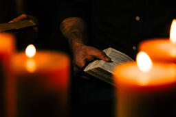 Man Reading Bible in Candle Lit Room  image 1