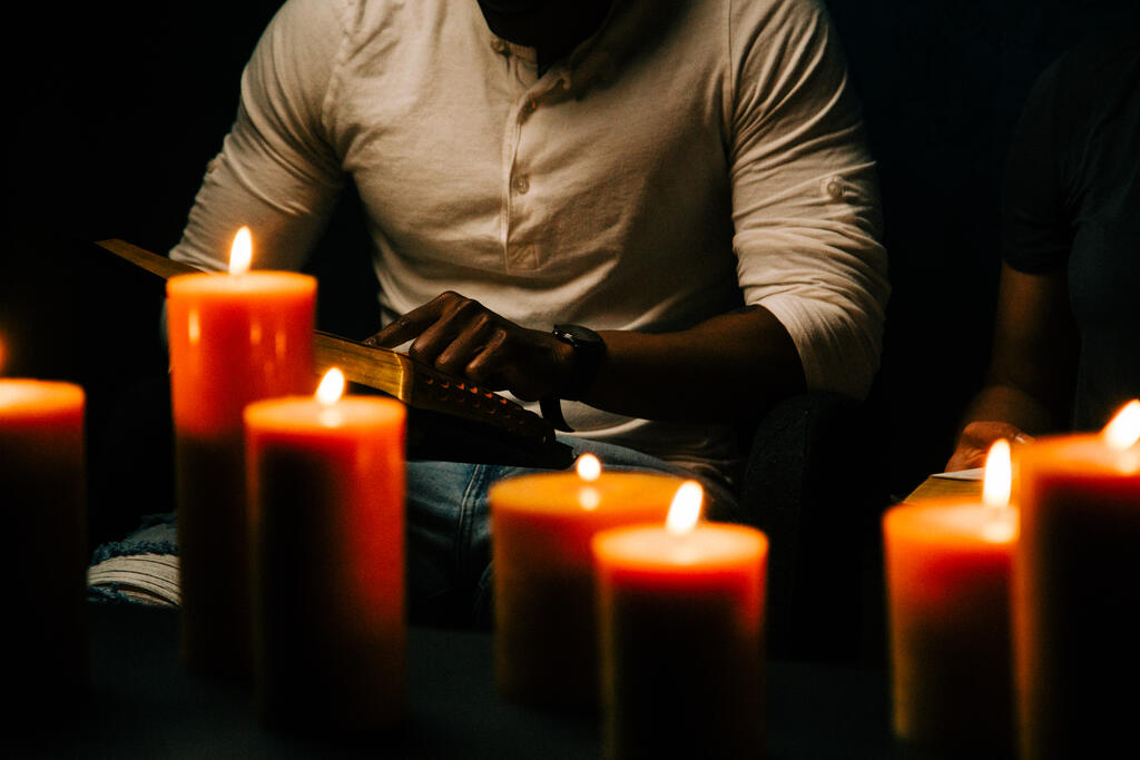 Man Reading Bible in Candle Lit Room large preview