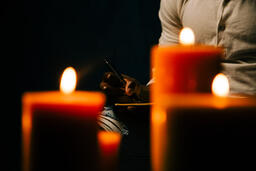 Man Writing in Notebook in Candle Lit Room  image 1
