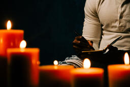 Man Writing in Notebook in Candle Lit Room  image 2
