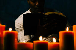 Man Reading Bible in Candle Lit Room  image 10