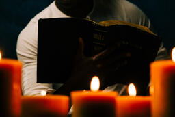 Man Reading Bible in Candle Lit Room  image 11