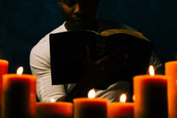 Man Reading Bible in Candle Lit Room  image 6
