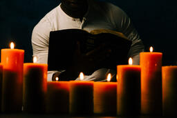 Man Reading Bible in Candle Lit Room  image 2