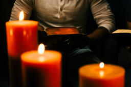 Man Reading Bible in Candle Lit Room  image 1