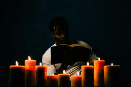 Man Reading Bible in Candle Lit Room  image 7
