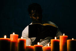Man Reading Bible in Candle Lit Room  image 5