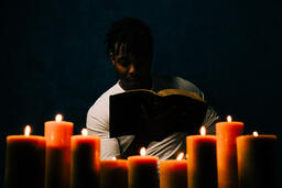 Man Reading Bible in Candle Lit Room  image 4