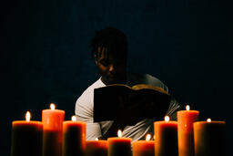 Man Reading Bible in Candle Lit Room  image 12