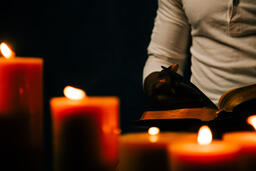 Man Reading Bible in Candle Lit Room  image 3