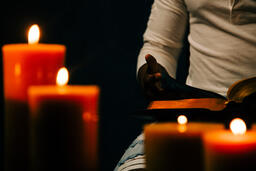 Man Reading Bible in Candle Lit Room  image 2