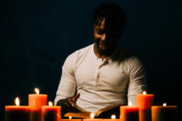 Man Reading Bible in Candle Lit Room  image 14