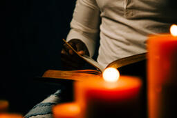 Man Writing in Notebook in Candle Lit Room  image 3