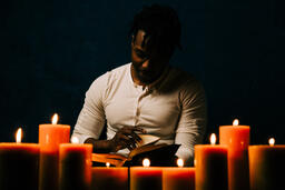 Man Reading Bible in Candle Lit Room  image 3