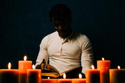Man Reading Bible in Candle Lit Room  image 12