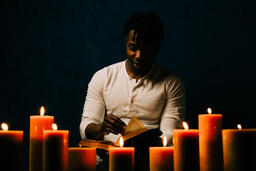 Man Reading Bible in Candle Lit Room  image 21