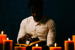 Man Reading Bible in Candle Lit Room  image 5