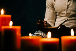 Man Writing in Notebook in Candle Lit Room  image 7
