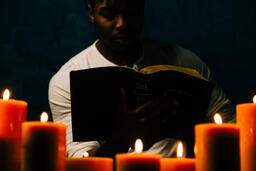 Man Reading Bible in Candle Lit Room  image 9