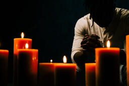 Man Praying in Candle Lit Room  image 4