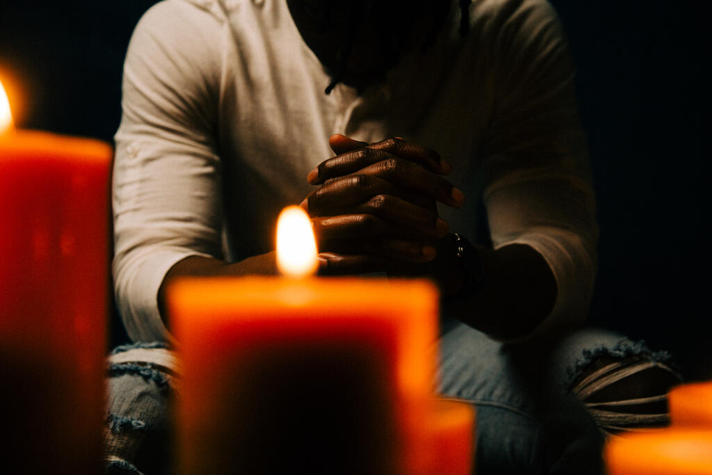 Man Praying in Candle Lit Room large preview
