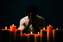 Man Praying in Candle Lit Room  image 2