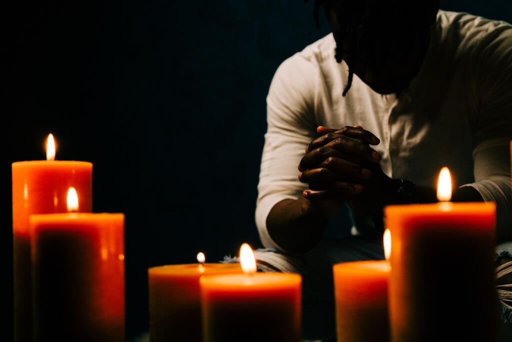 Man Praying in Candle Lit Room large preview