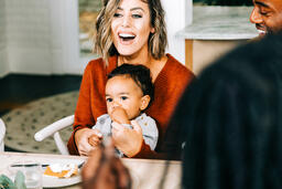 Woman Laughing at Thanksgiving Table, Holding Baby  image 2