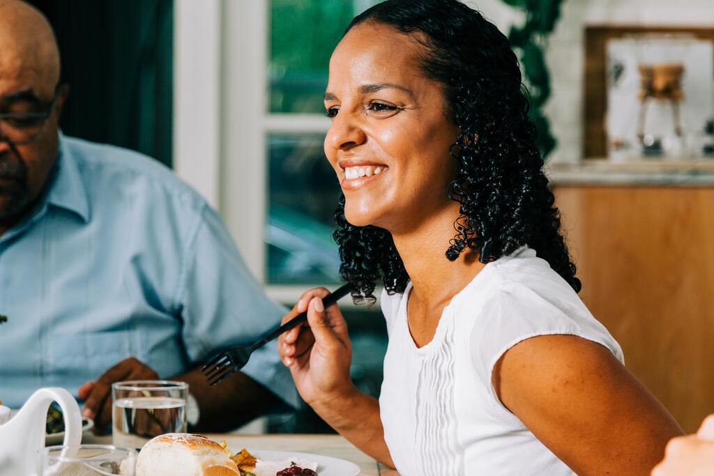 Woman Laughing with Family and Enjoying Thanksgiving Dinner large preview
