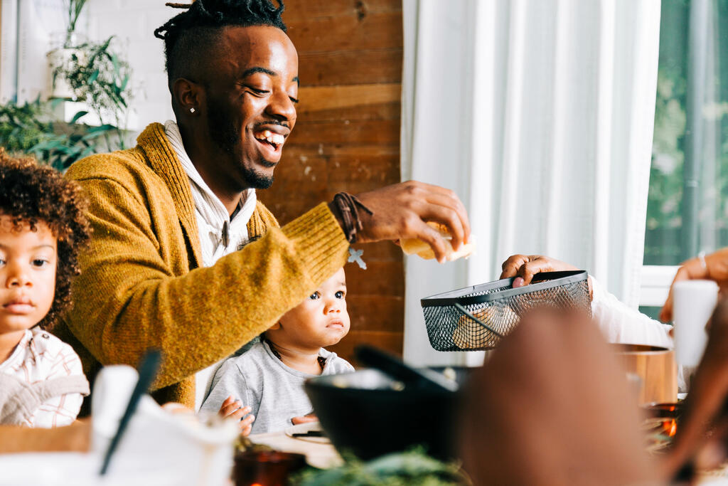 Man Grabbing a Dinner Roll From the Bread Basket at Thanksgiving Dinner large preview