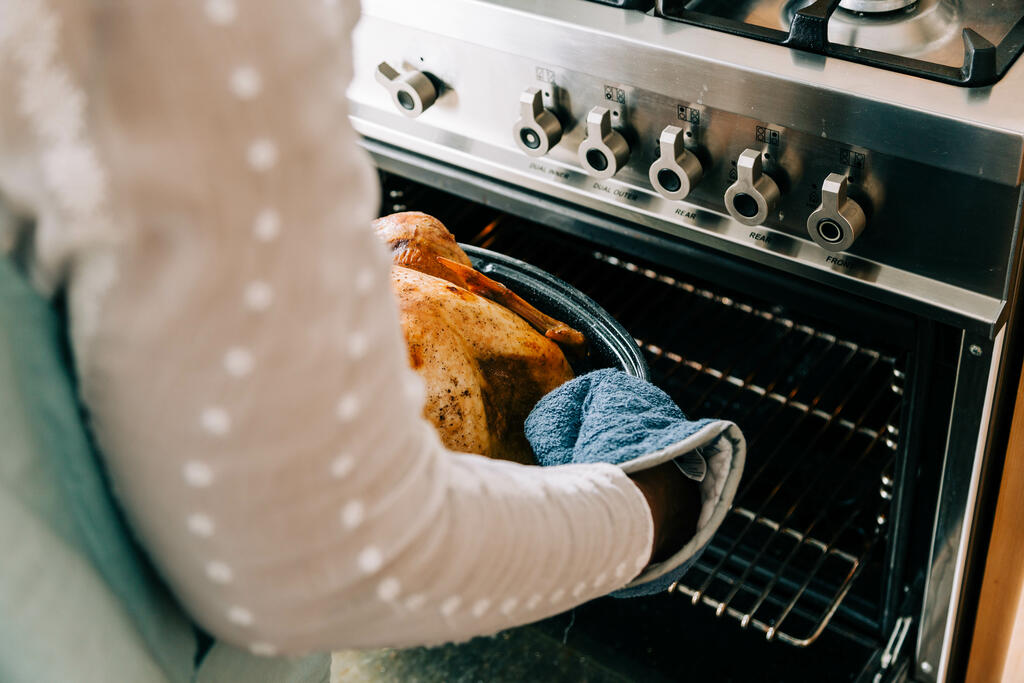 Woman Pulling Thanksgiving Turkey Out of the Oven large preview