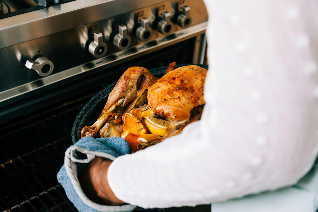 Woman Pulling Thanksgiving Turkey out of the Oven large preview